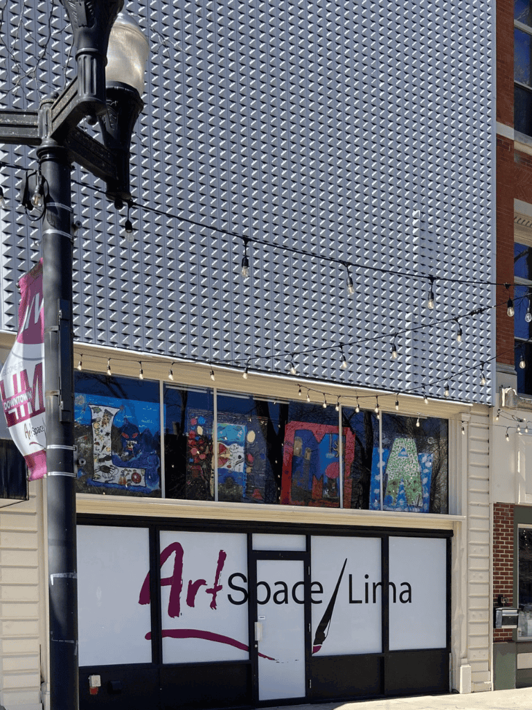Colorful art gallery storefront with vibrant mosaic window art, located in downtown Linna.