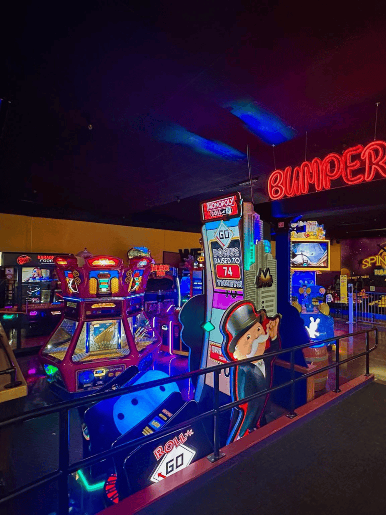 Arcade games with colorful neon lights at QuestForDirections entertainment center in the image.