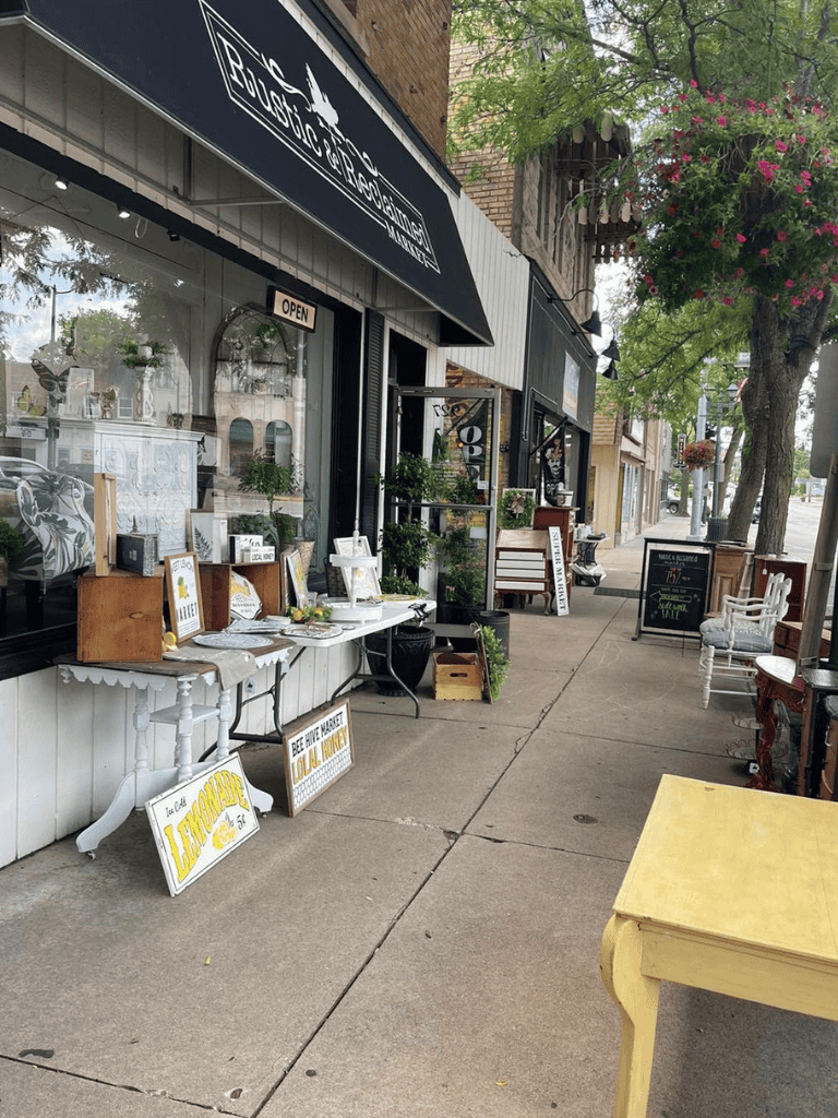 Colorful antique shop with outdoor displays and blooming trees, perfect for exploring unique home decor and vintage items.