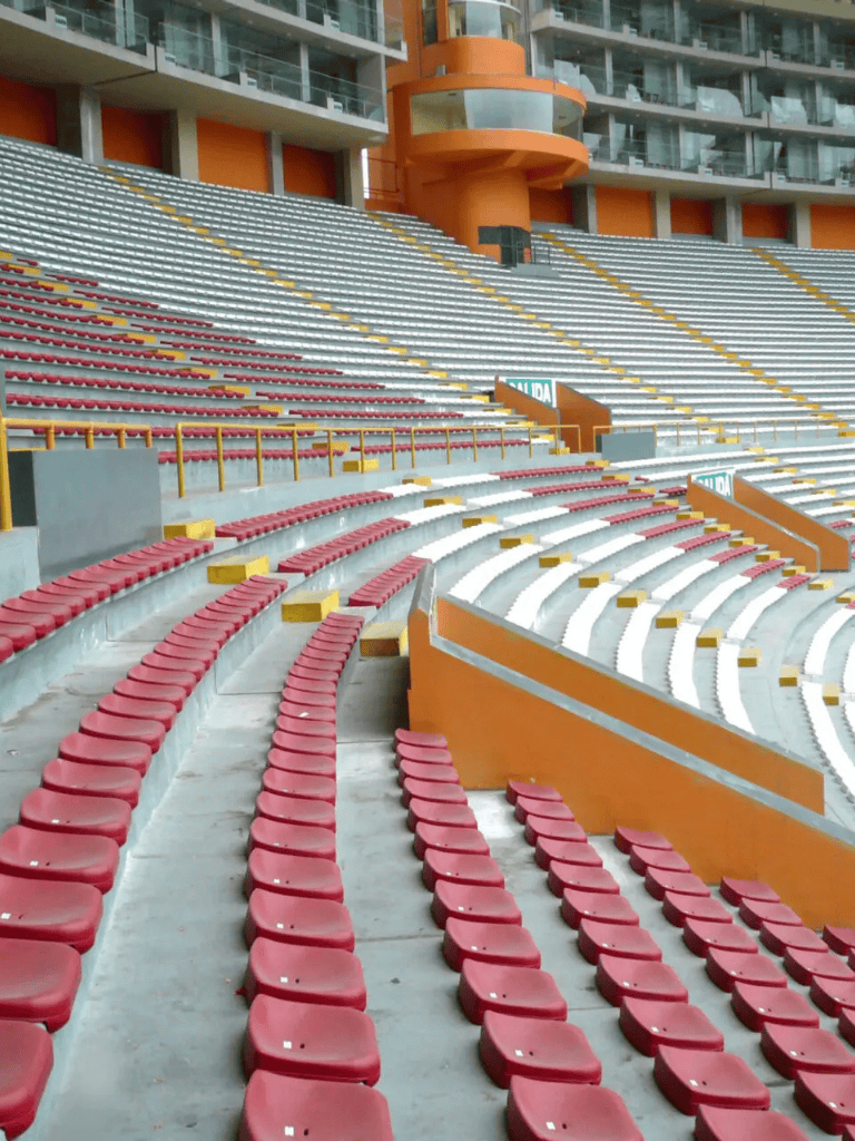 Red stadium seats in a modern outdoor sports arena with orange structural elements.