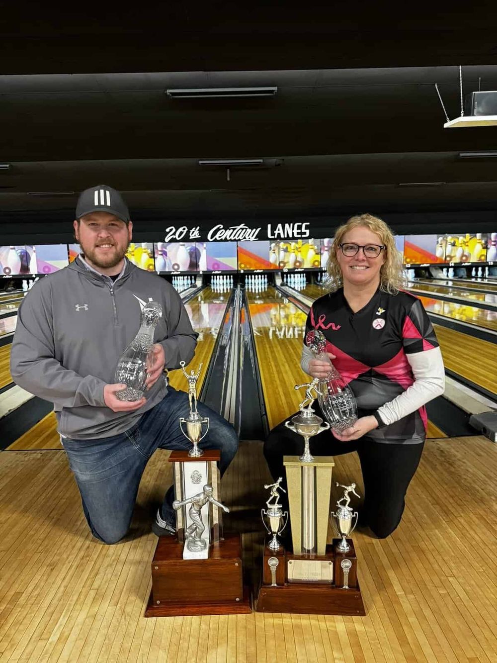 Keen bowlers with trophies and crystal awards at the bowling alley, celebrating victory and achievements.