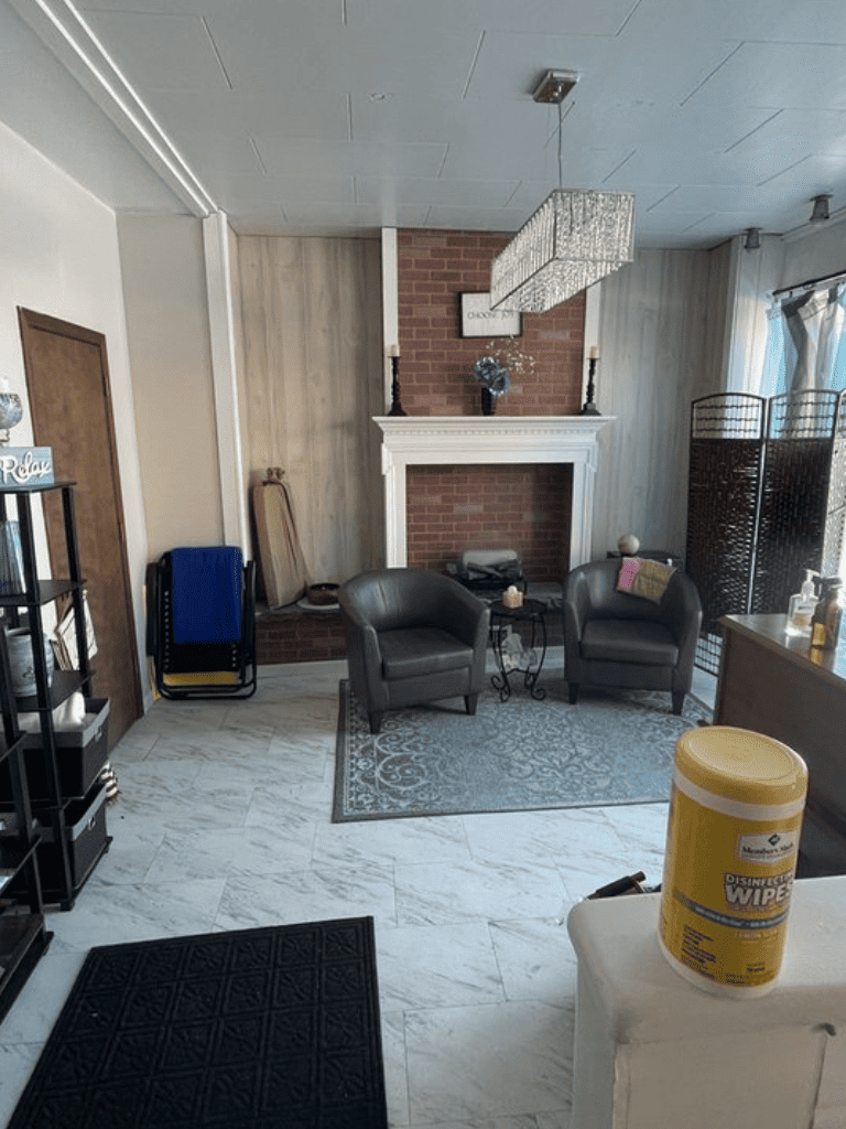 Cozy living room with brick fireplace, modern chandelier, and comfortable seating area.