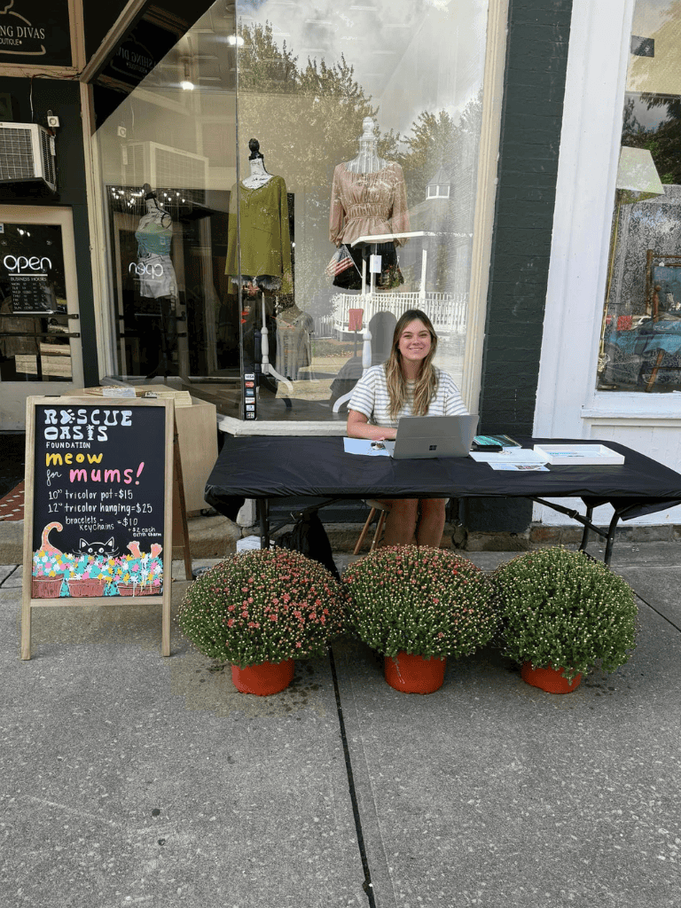 Friendly woman sitting at outdoor registration table for local charity event with mumsplants.
