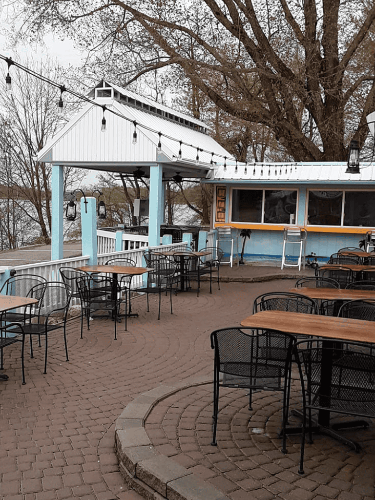 Outdoor dining area at a restaurant with string lights and a covered patio, perfect for social gatherings and dining.