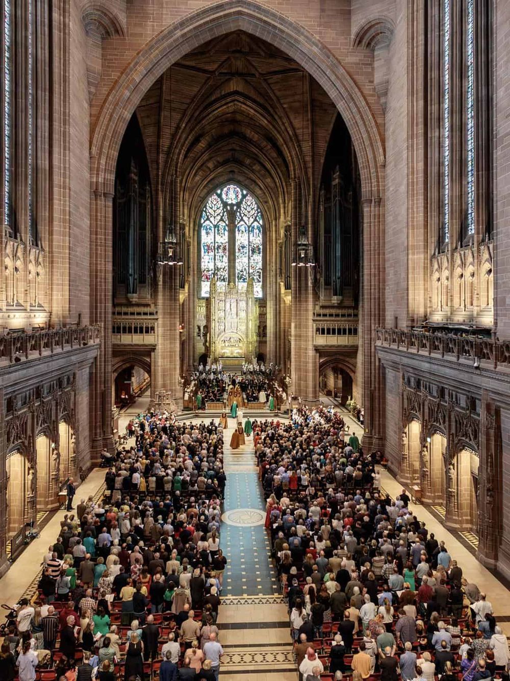 Stunning church interior during ceremony with stained glass windows and large congregation.