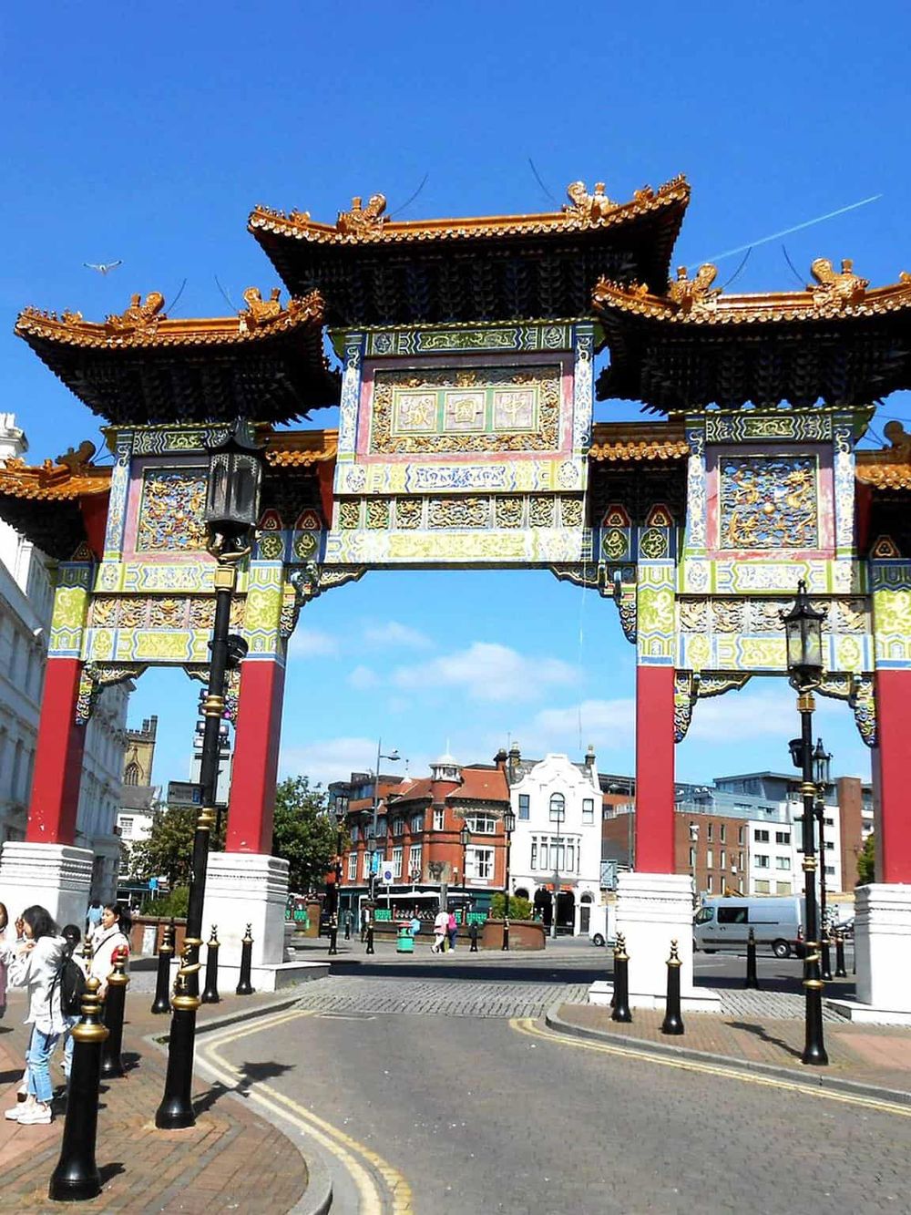 Colorful Chinatown arch in London, illuminated under a clear blue sky, welcoming visitors to Chinatown district.