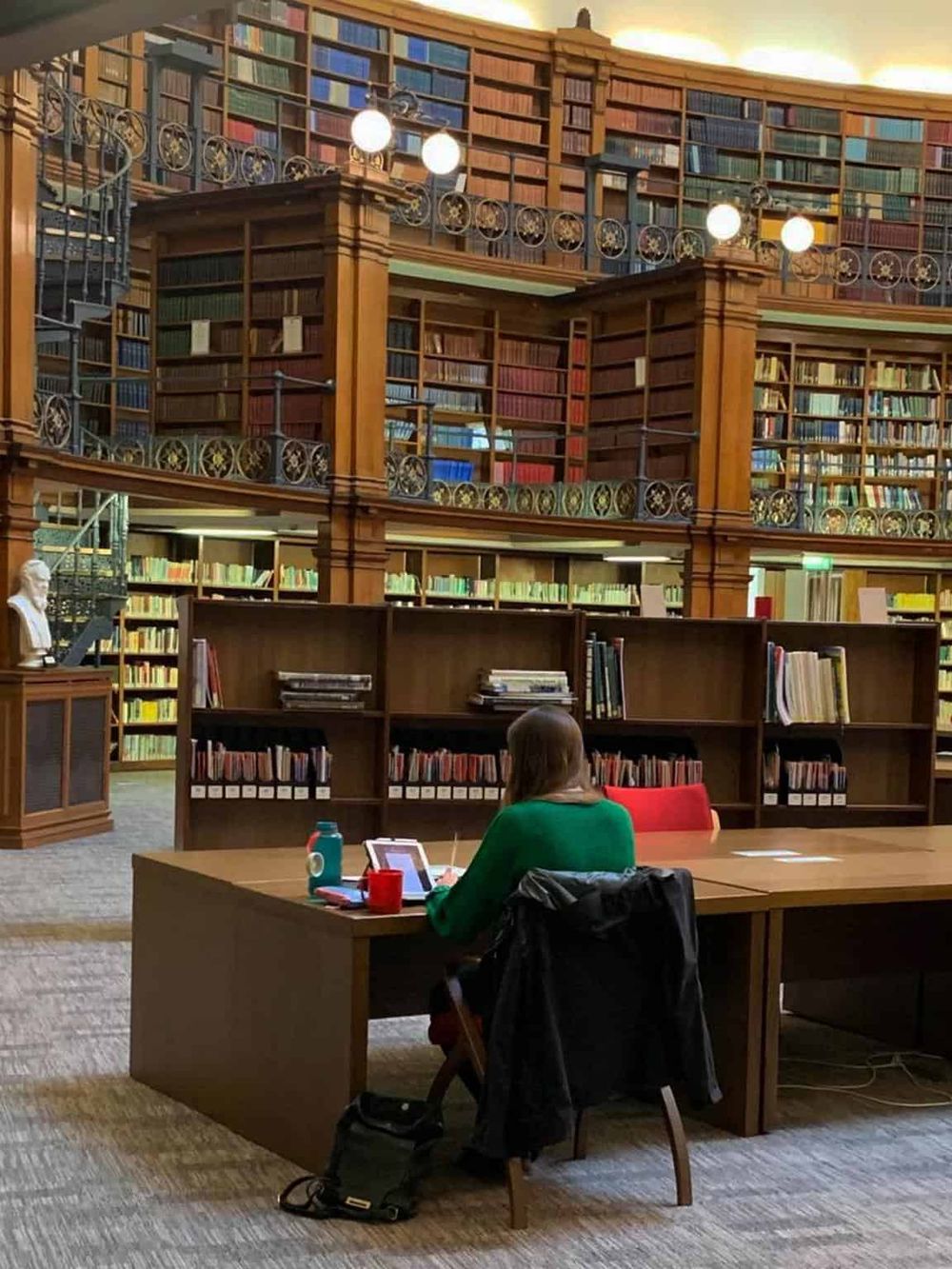 Quiet library reading and studying in a grand multi-level wooden bookstore with tall bookshelves.