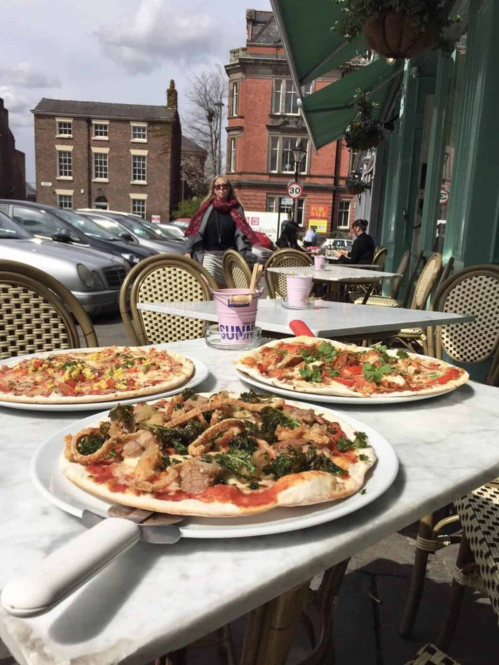 Delicious pizzas served at an outdoor cafe, offering a cozy dining experience in a charming city street setting.