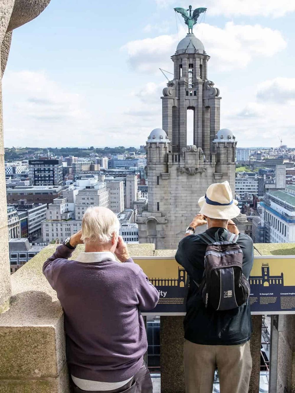 Spectators enjoying city views from a high vantage point in Liverpool, showcasing iconic architecture and skyline.