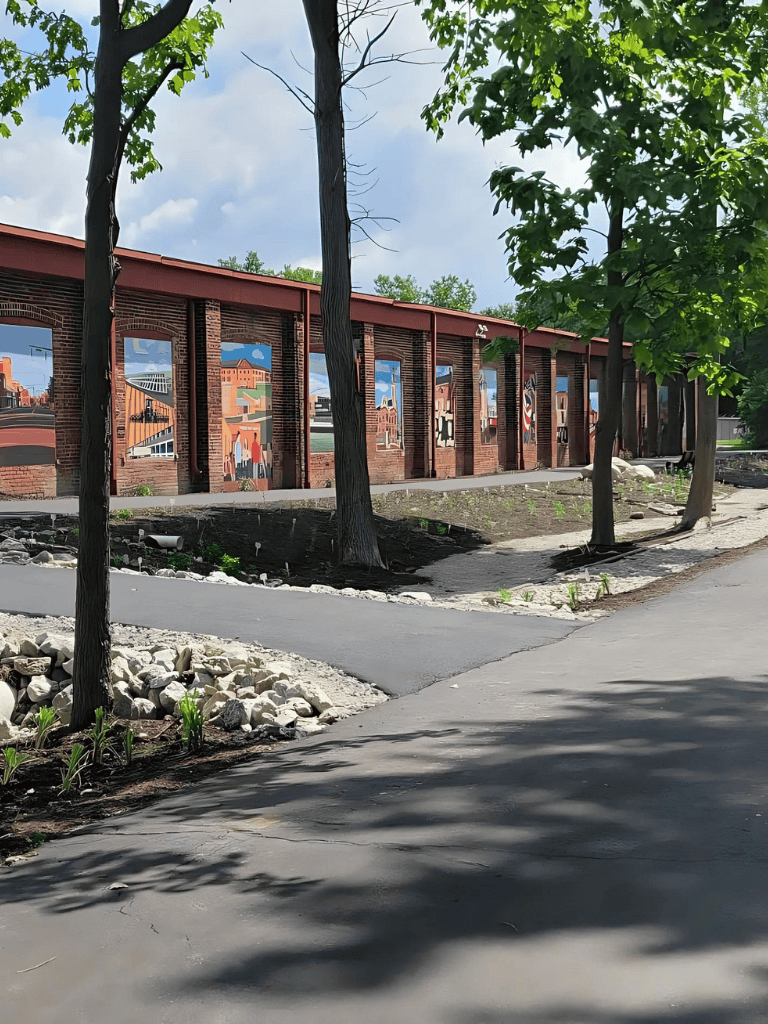 Historic brick mural wall featuring colorful cityscape art in an outdoor park setting.