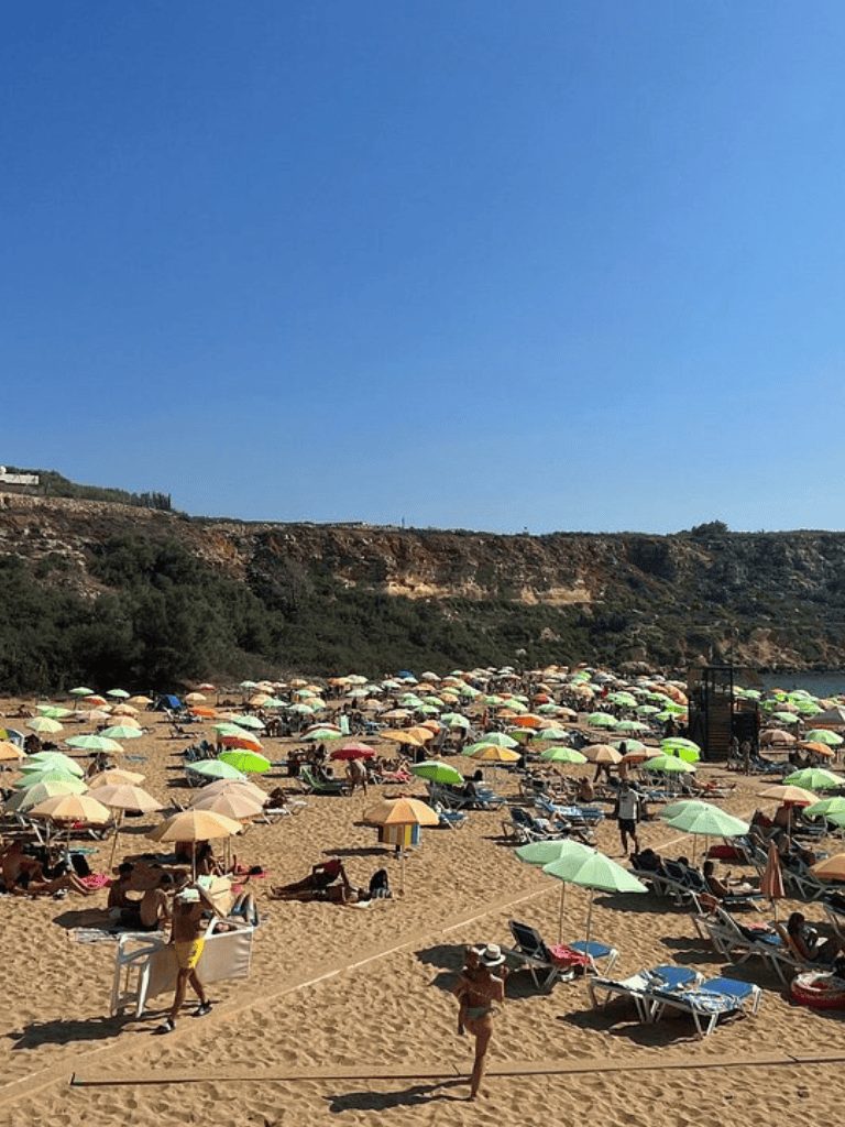Sunny beach with colorful umbrellas and lounging visitors, perfect for a relaxing summer getaway.
