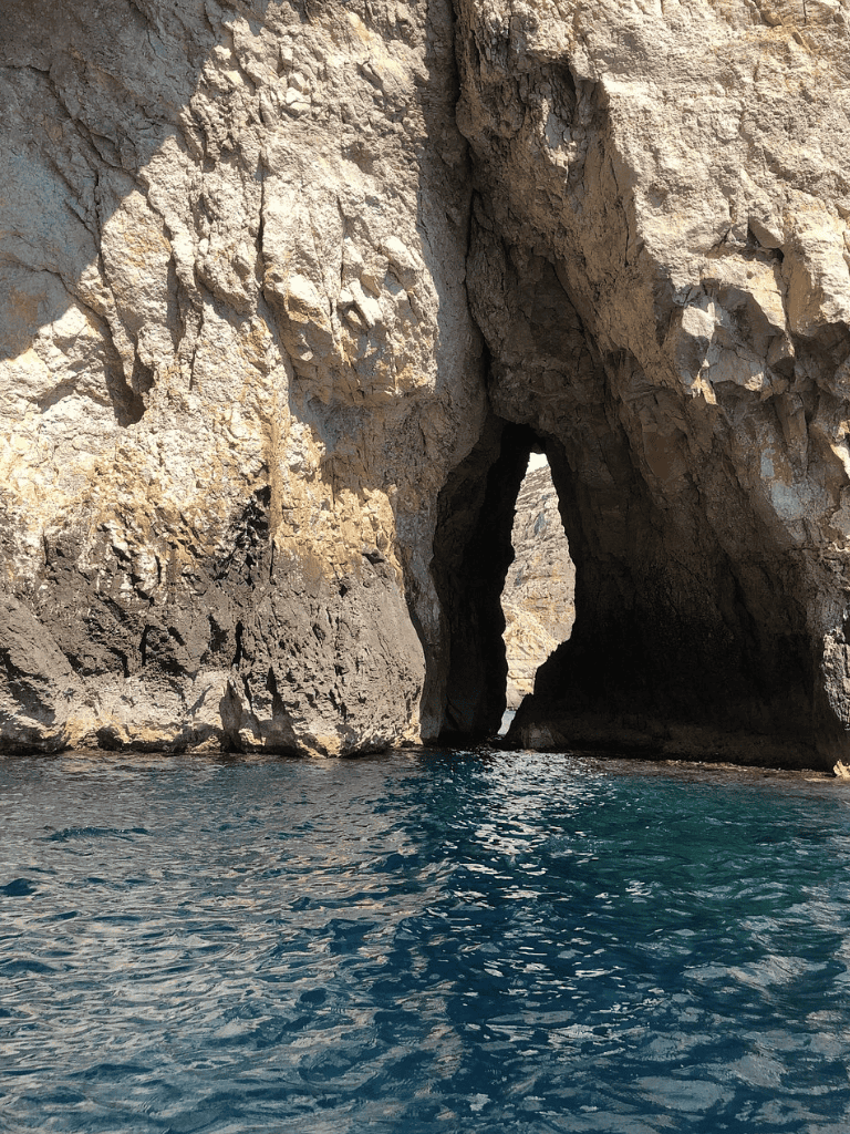Secluded sea cave with towering rock cliffs and clear blue waters, perfect for exploration and adventure.