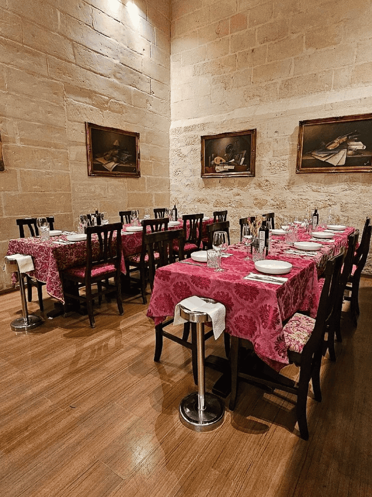 Elegant restaurant dining room with pink floral tablecloths and classic wooden chairs.