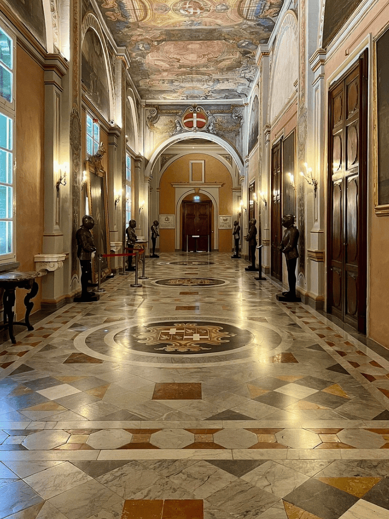 Ornate historic hallway with sculptures and intricate ceiling murals, part of QuestForDirections historical tour.
