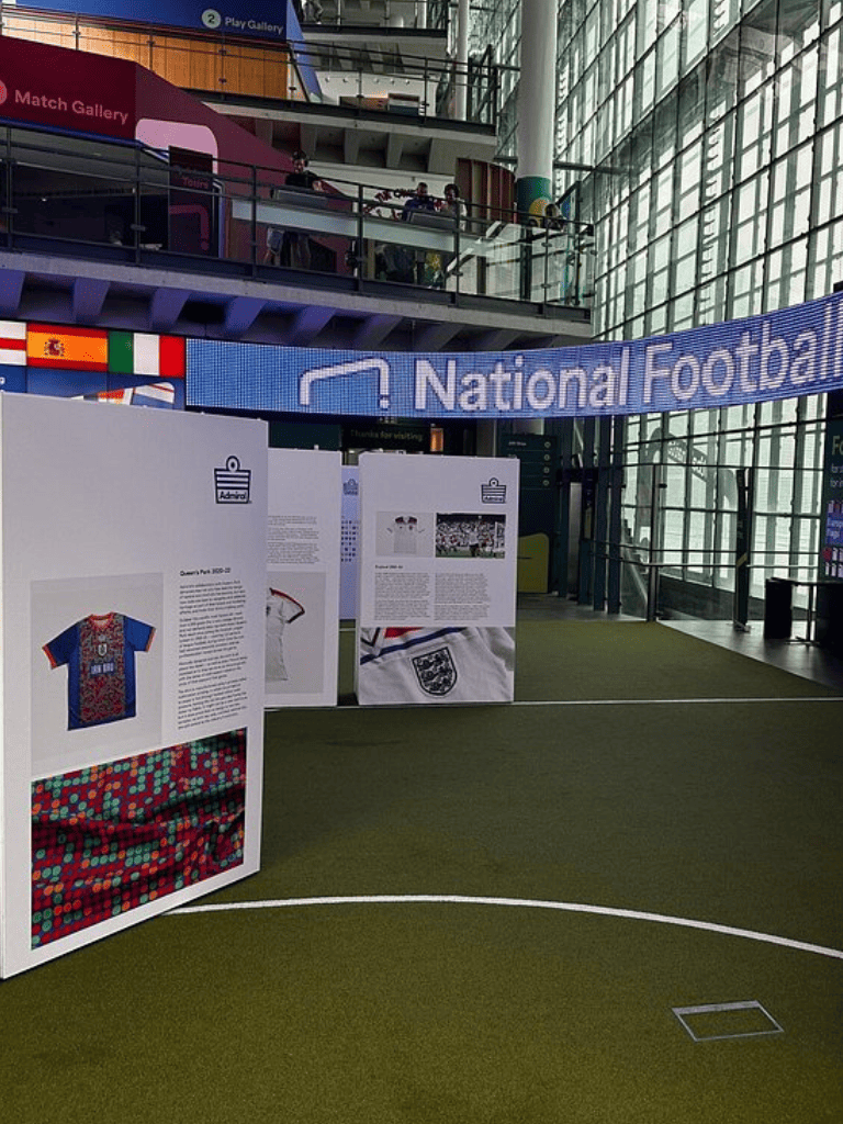 Colorful football memorabilia and display panels at National Football exhibit in a modern indoor stadium.