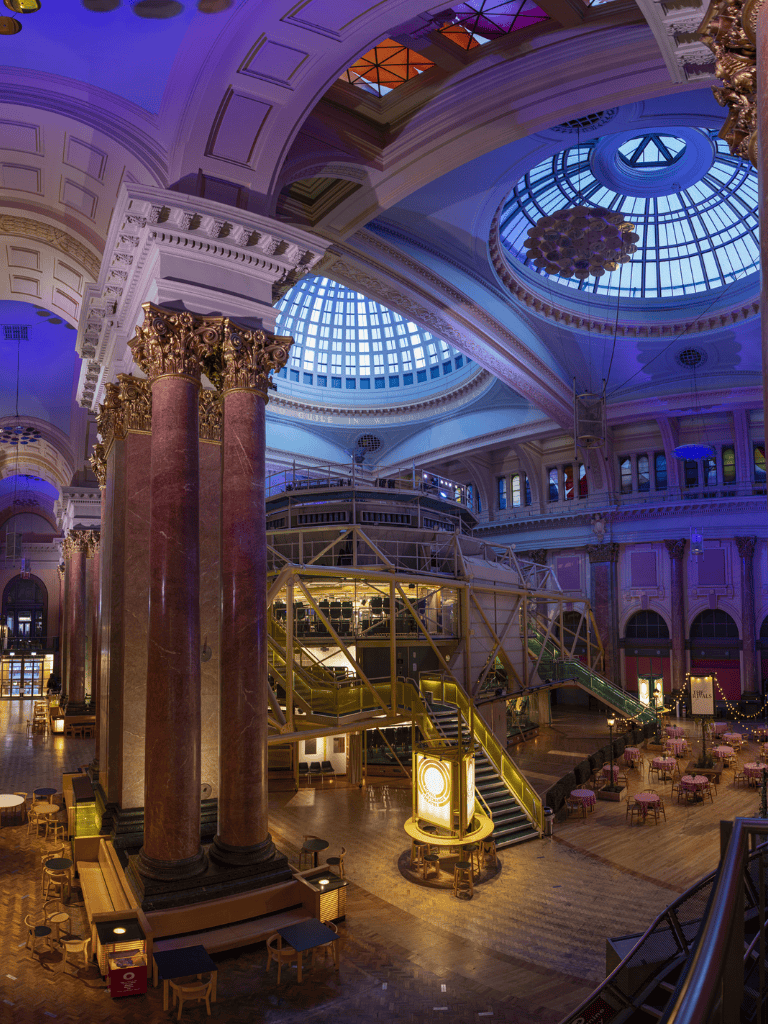 Luxurious historic hotel interior with grand domed ceiling and ornate columns, elegant lighting, and seating arrangements.