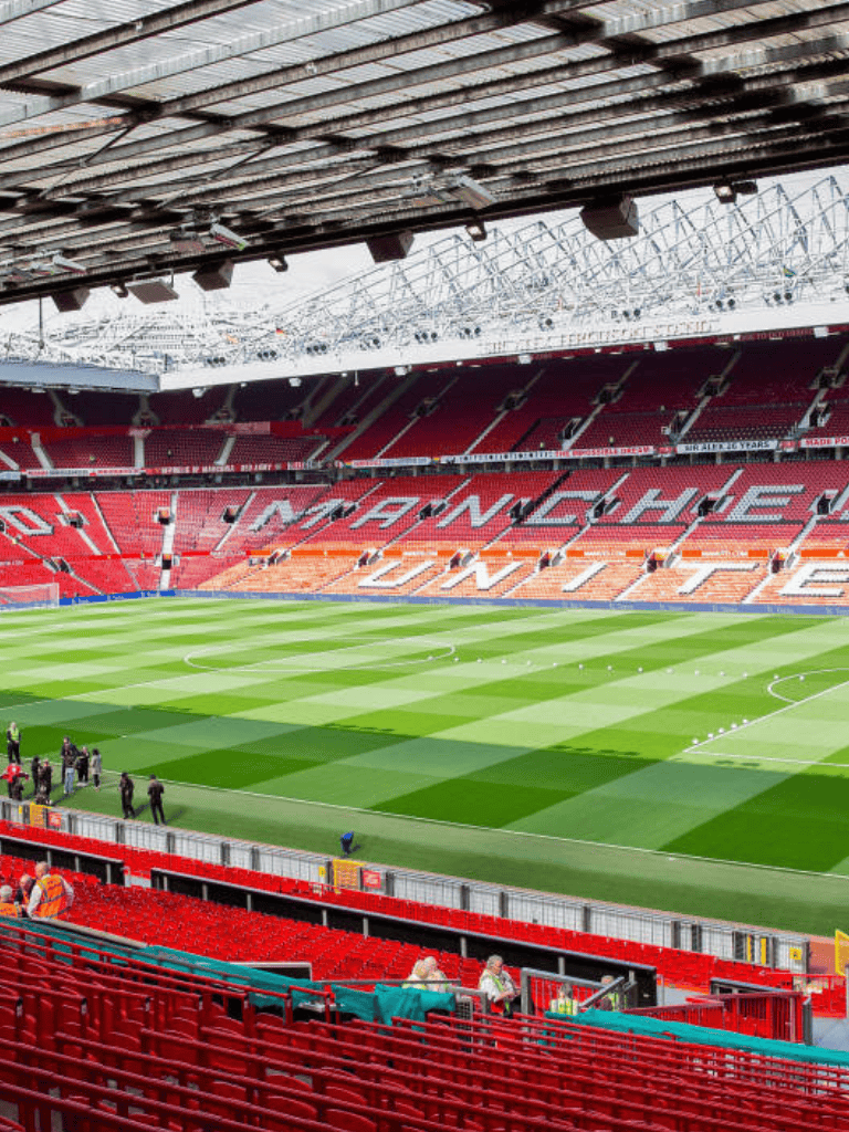 Bright Manchester United stadium with green pitch and red seating, home of legendary football matches.