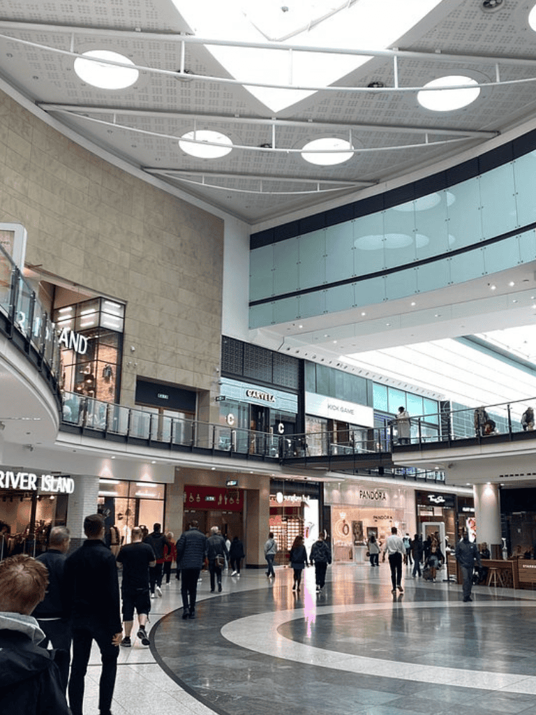 Outdoor shopping mall with visitors, luxury stores, and modern architecture.