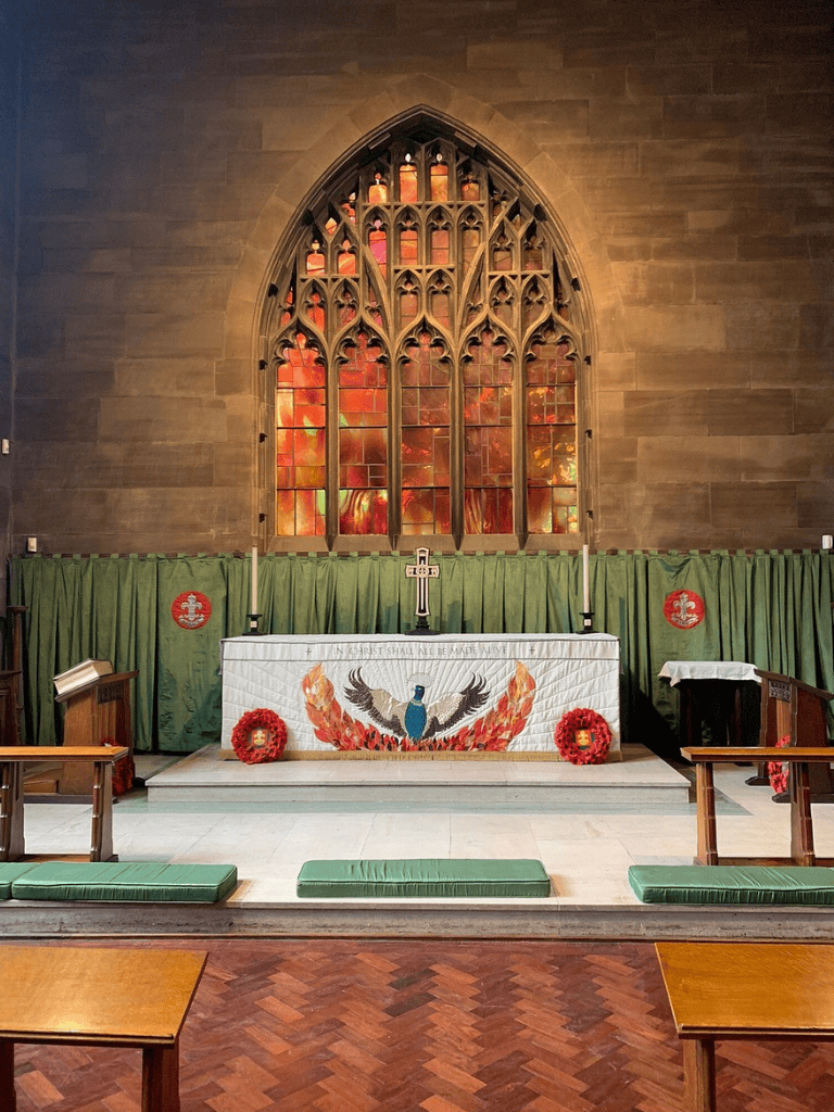 Altar inside church with stained glass window and patriotic decorations for Memorial Day service.
