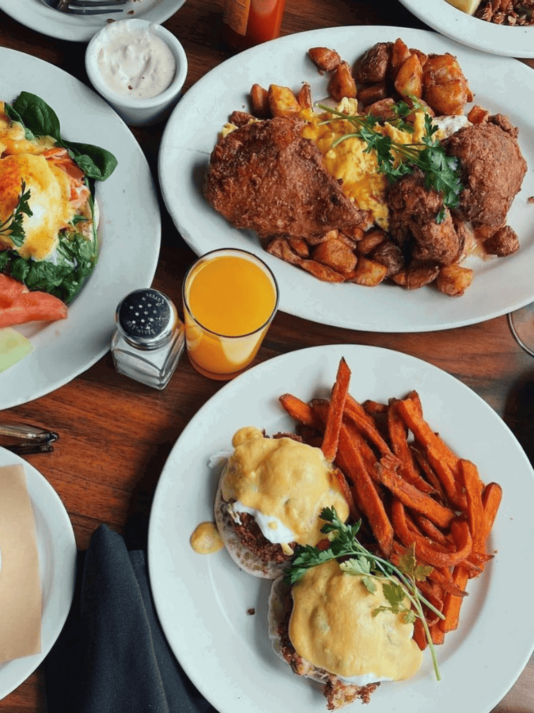 Crunchy fried chicken with herbs, sweet potato fries, and cheesy biscuits on a white plate.