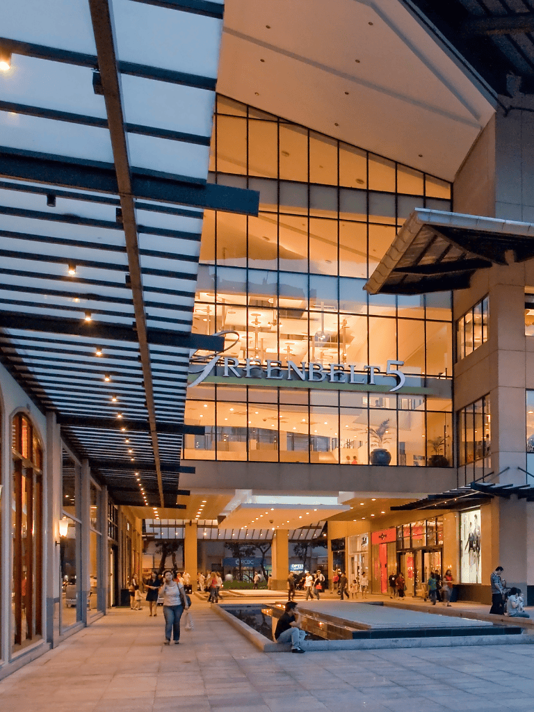 Modern shopping mall exterior with glass facade and bustling shoppers in en_US.
