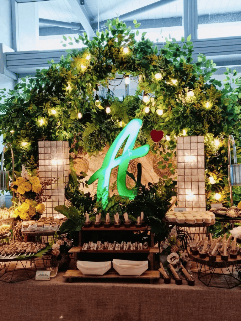 Celebration decor with lush greenery, illuminated "A" sign, and floral arrangements at QuestForDirections.