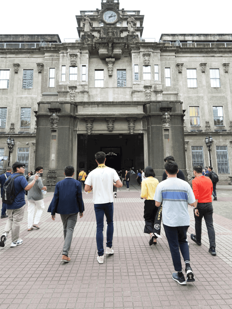 Historic building with clock tower and group of diverse tourists exploring downtown city.