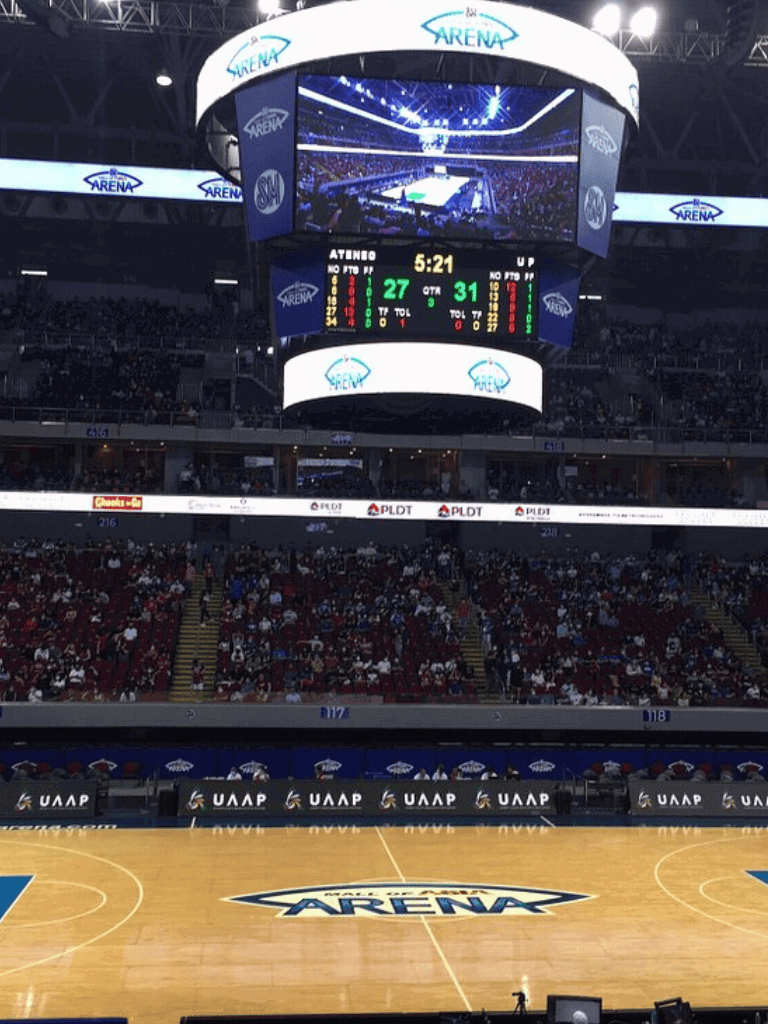 Arena sports scoreboard at QuestForDirections basketball game, digital screen display, and stadium seating.