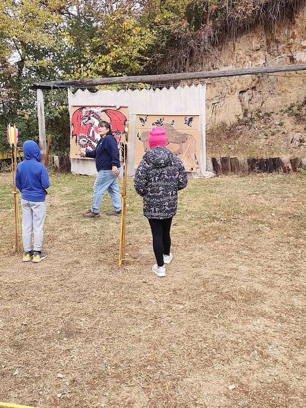 Colorful medieval-themed outdoor puppet show for children, set against rocky hillside and autumn trees.