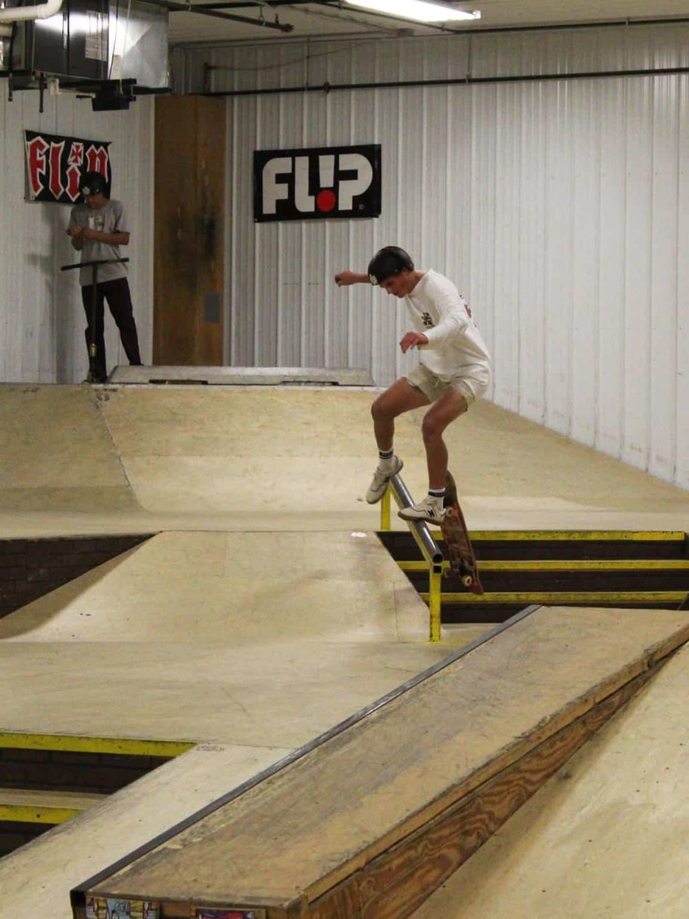 Skateboarder performing tricks at indoor skatepark for skateboarding enthusiasts.