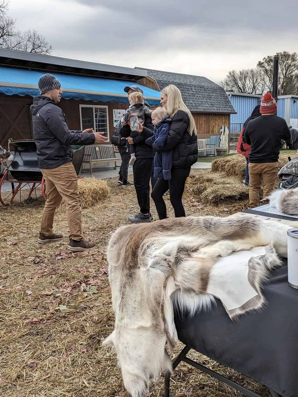 1. People at a farm or animal petting zoo event, engaging with farm attendants.