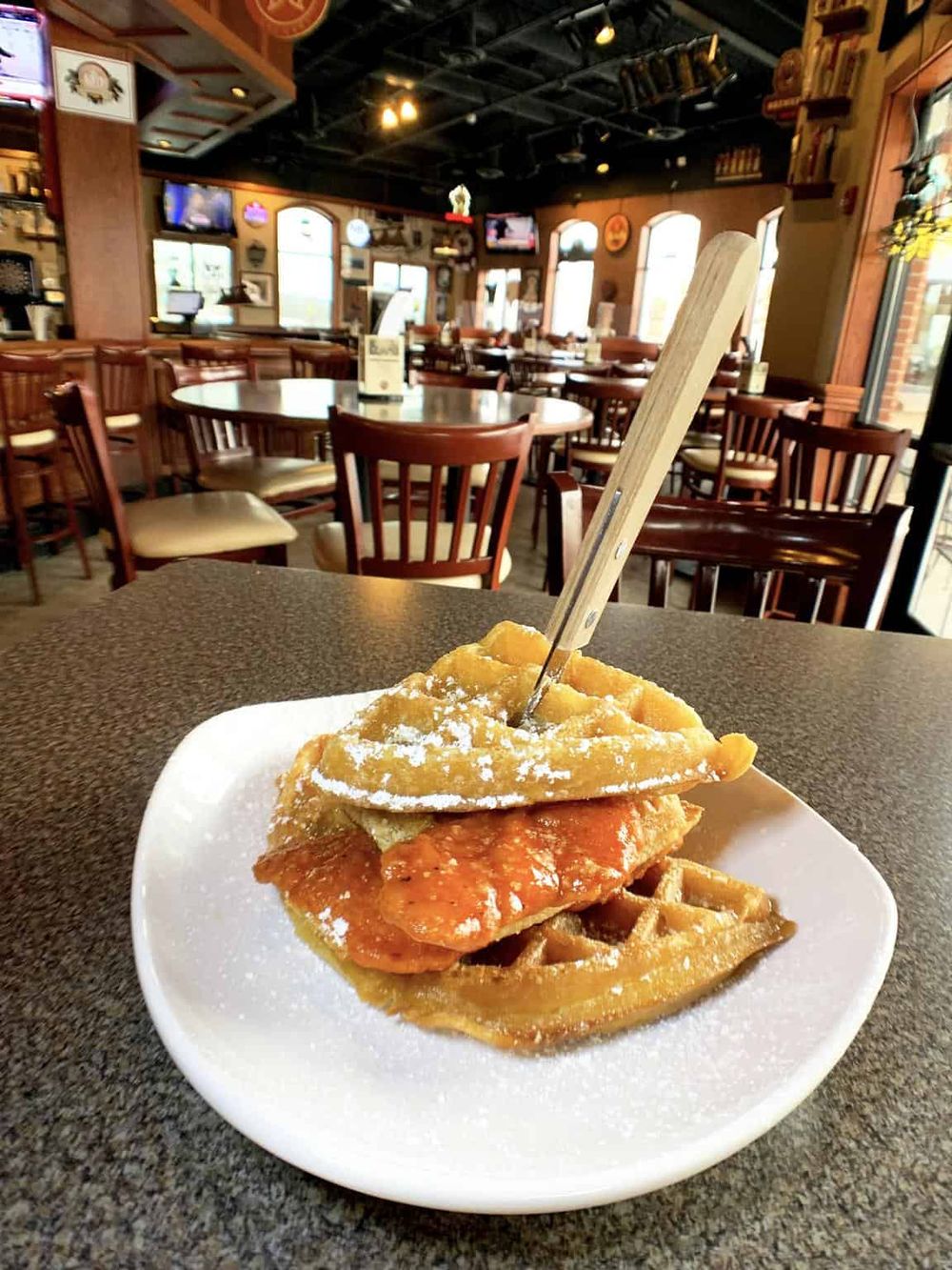 Delicious chicken and waffle appetizer on a white plate in a cozy restaurant setting.