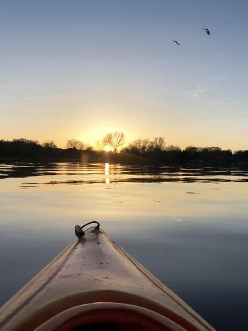 Serene kayak sunset scene over calm water, highlighting outdoor adventure and navigation.