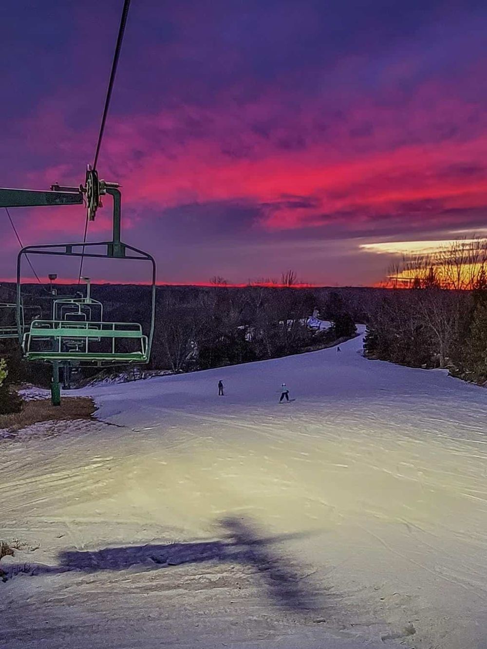 Vibrant winter sunset over a ski slope with chairlift, showcasing scenic snowboarding and skiing destination.
