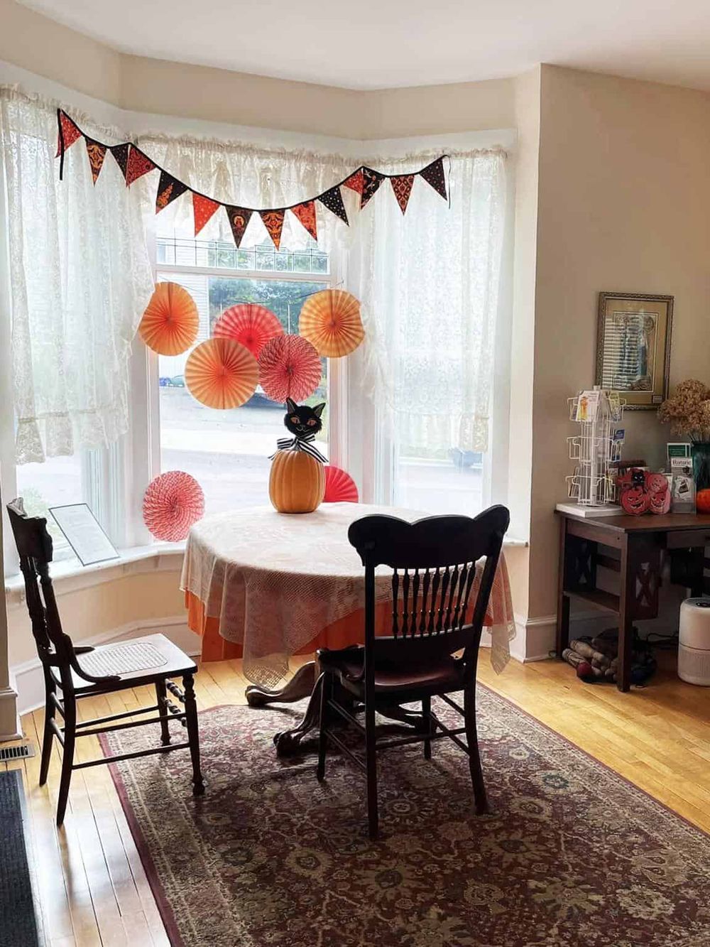 Colorful Halloween decorations in a cozy dining room with a round table, paper lanterns, and festive bunting, creating a cheerful spooky atmosphere.