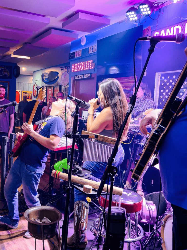 Music performance at QuestForDirections, vibrant live band and lively crowd in a colorful bar environment.