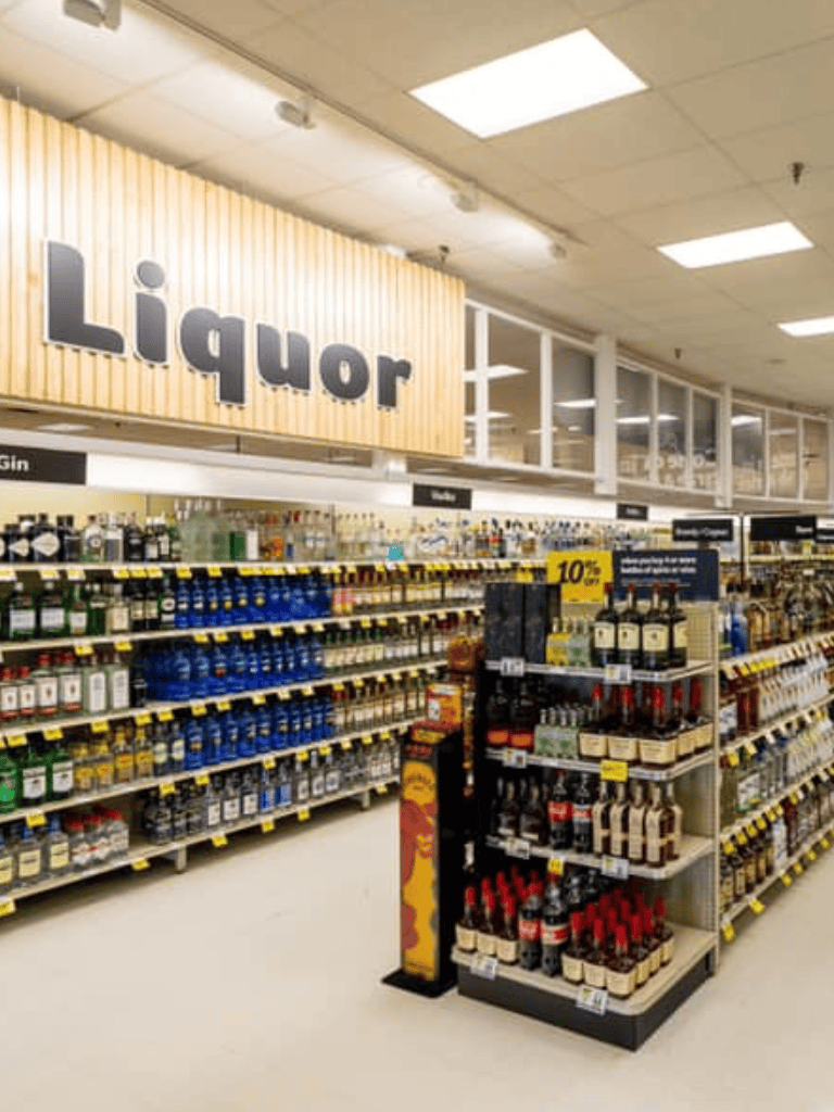 Liquor store aisle with alcohol bottles and signage for liquor section.