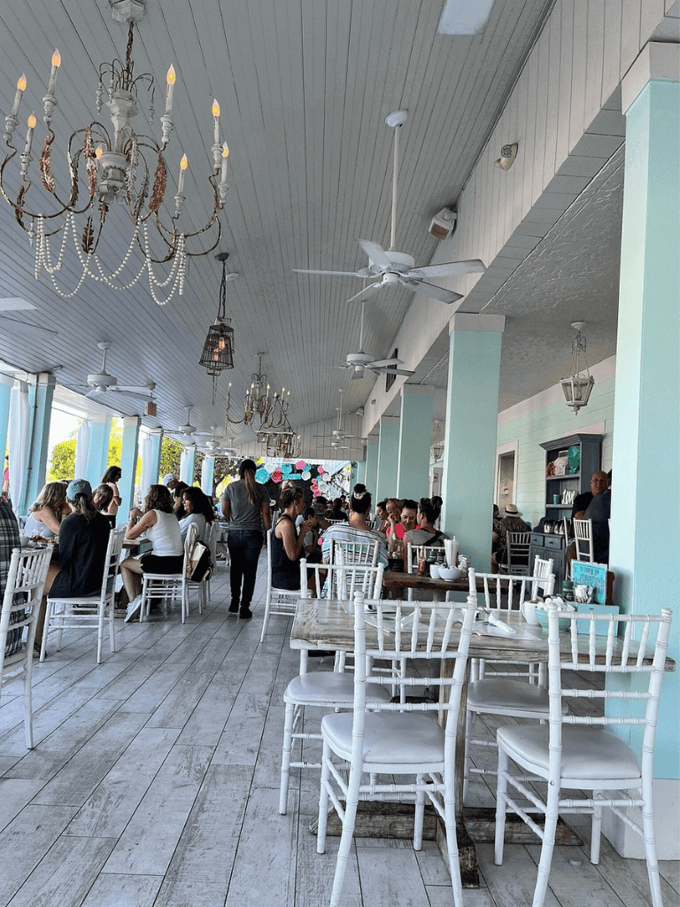 Charming beachfront restaurant interior with chandeliers and ceiling fans, perfect for dining with ocean views.