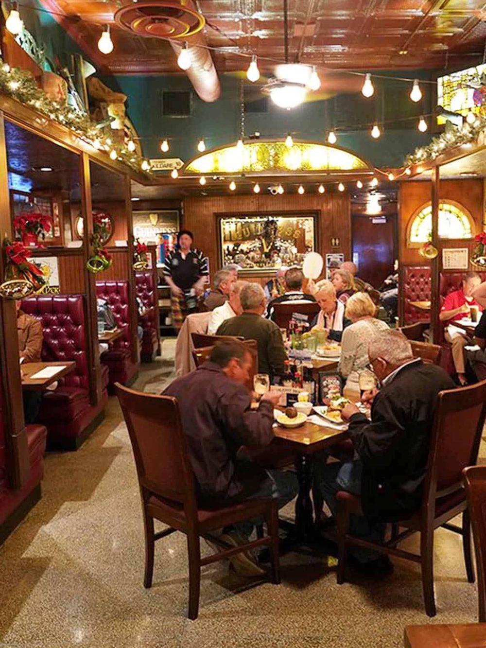 Cozy restaurant interior with customers enjoying meals, warm lighting, and festive holiday decorations.
