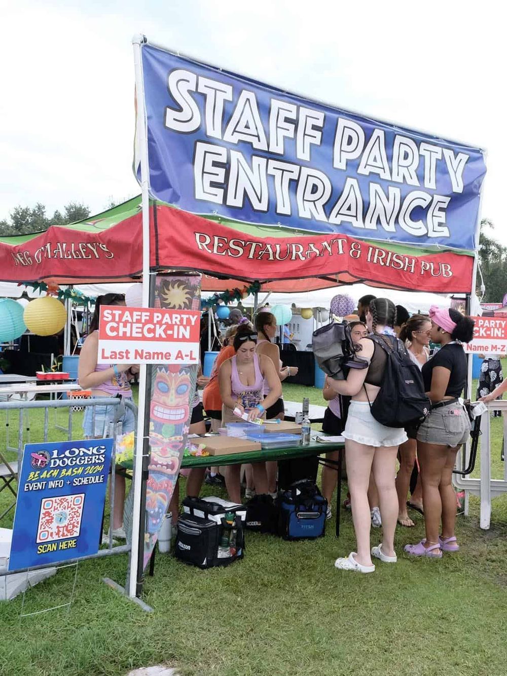 Staff party entrance at outdoor event with people signing in and colorful decorations.