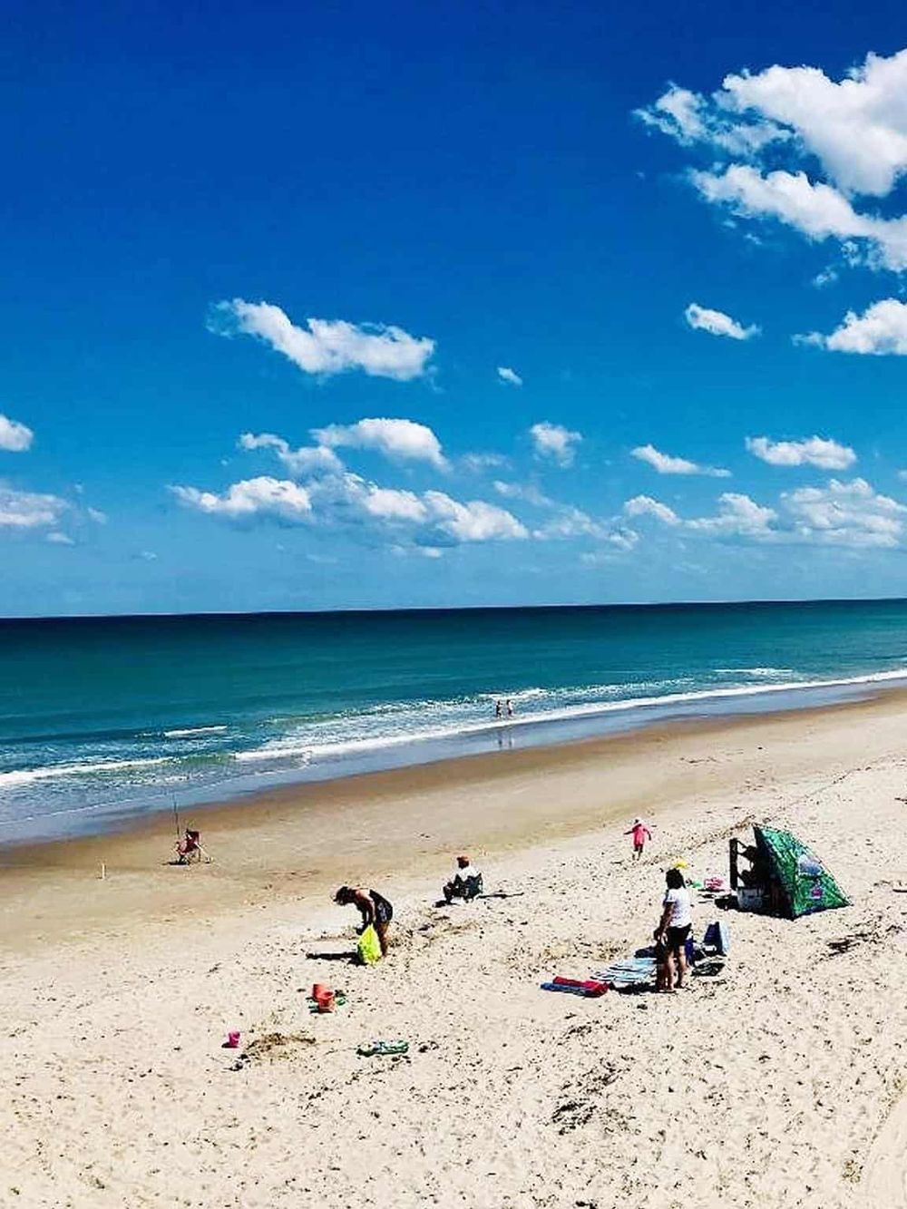 Sunny beach with people enjoying sand and sea, perfect for family vacation and outdoor activities.