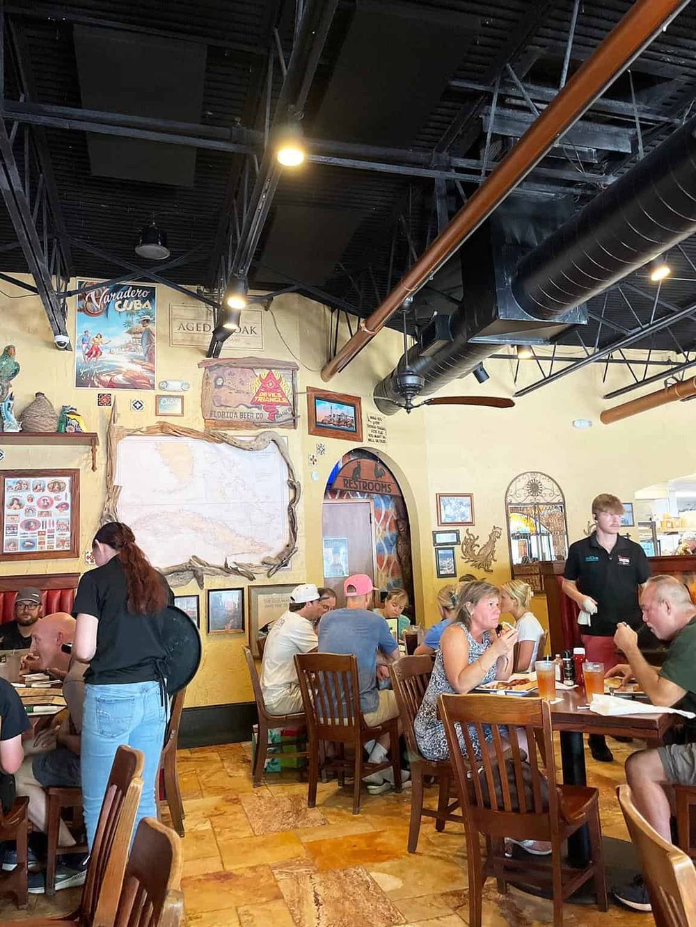 Bustling restaurant interior with colorful decor, wooden furniture, and guests enjoying meals, highlighting vibrant dining atmosphere.