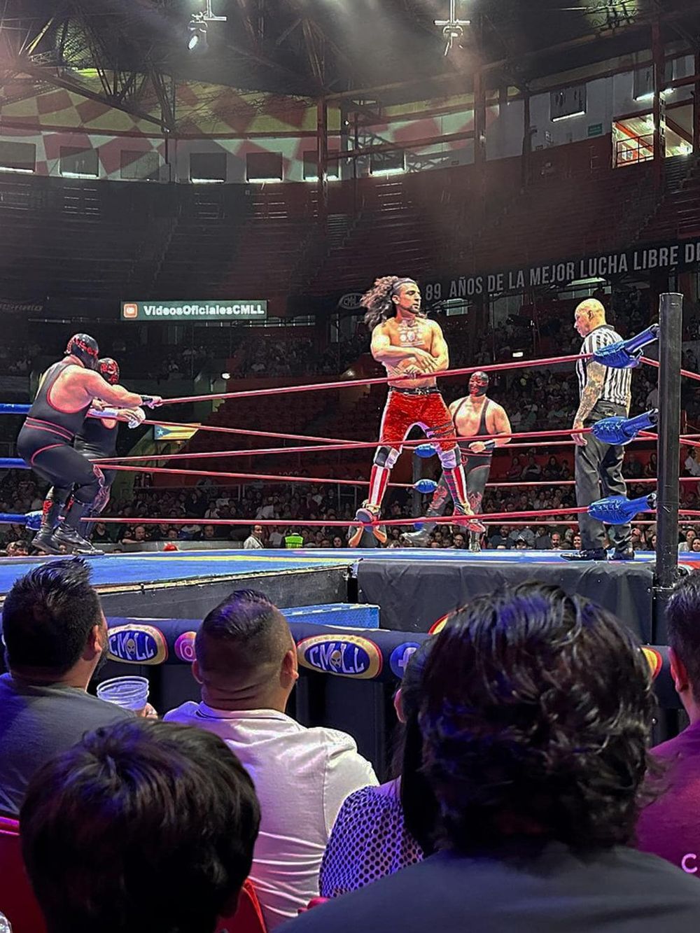 Lucha libre wrestling match spotlight at QuestForDirections event with energetic crowd and vibrant ring action.