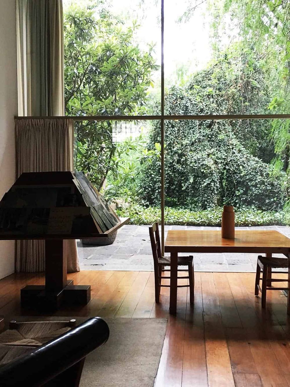 Tranquil indoor space with large window view of lush green garden, ideal for relaxing or working.