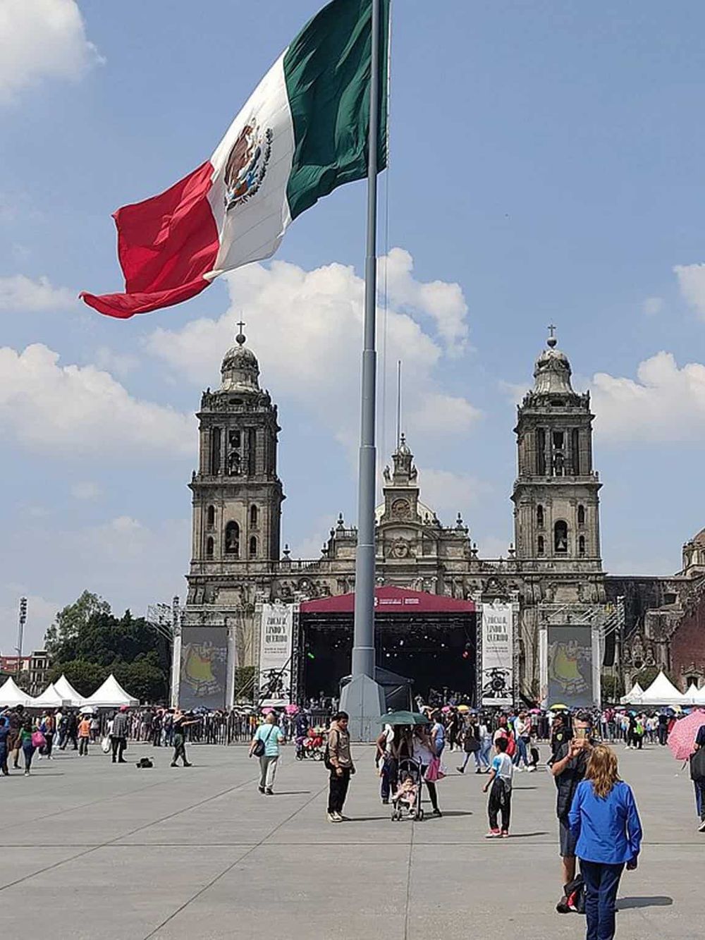 Mexican flag flying in front of a historic cathedral in Mexico City, vibrant cultural landmark.