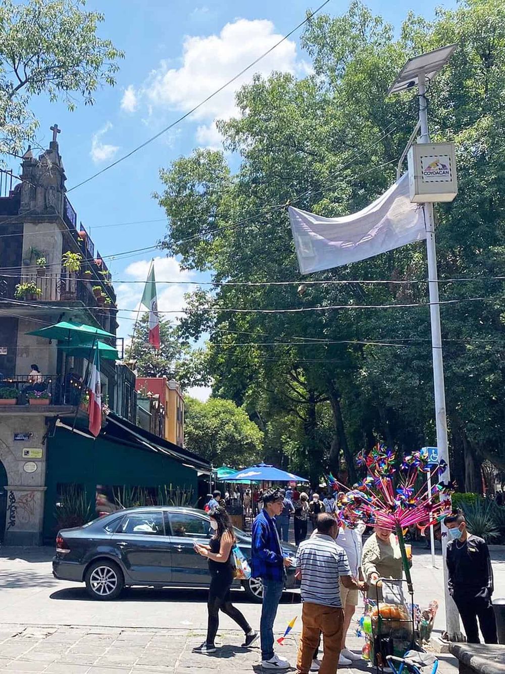Colorful street scene with pedestrians, storefronts, and a flag in a lively urban setting, promoting QuestForDirections.