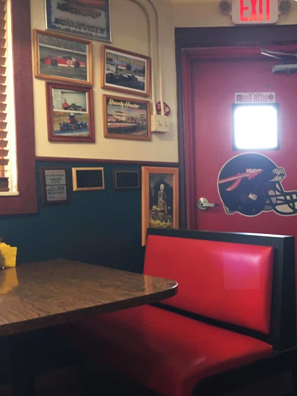 Colorful restaurant corner with racing car artwork and vintage photos, cozy booth seating and vibrant decor.