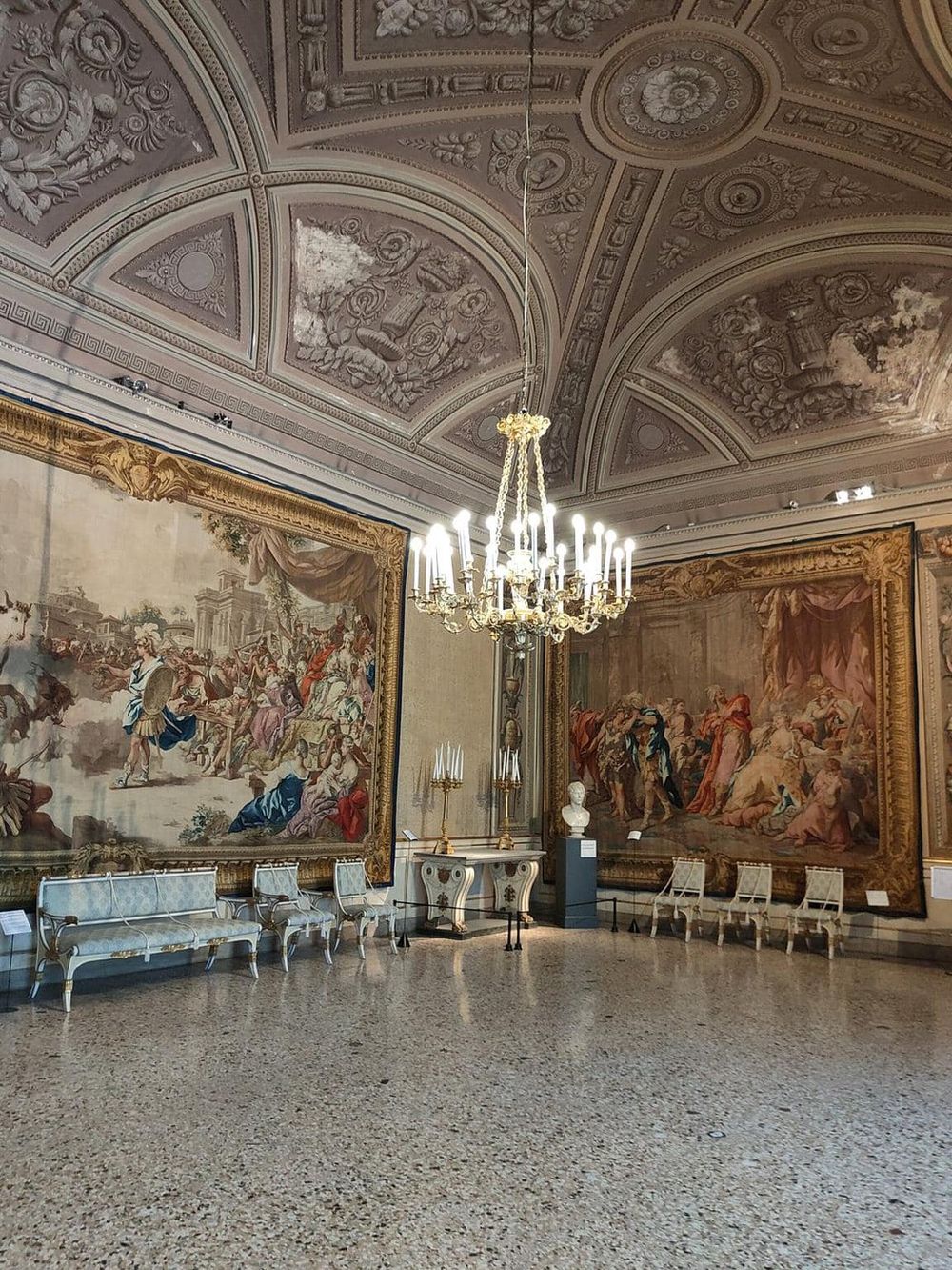 Ornate historic art museum interior with classical paintings, chandelier, and elegant furnishings.