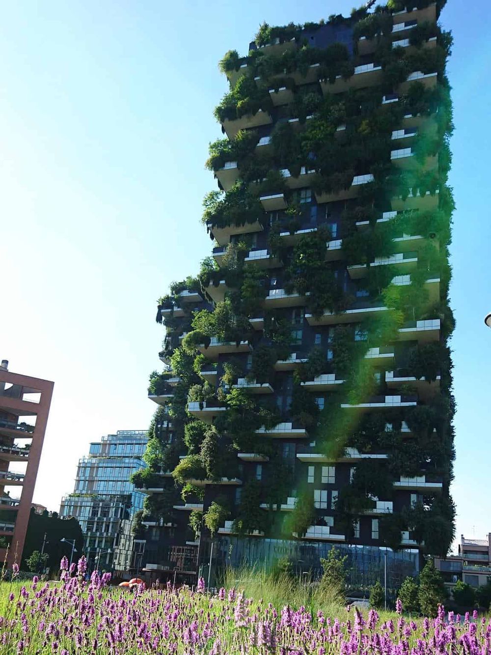 Modern green rooftop skyscraper with lush gardens and trees.