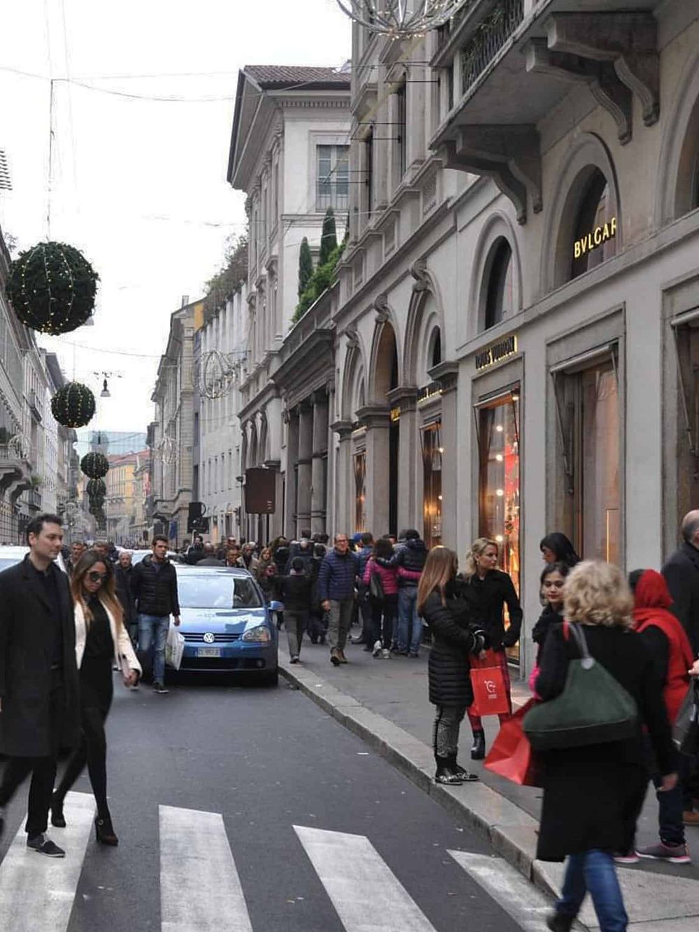 Bustling shopping street in Europe featuring luxury boutiques and holiday decorations.